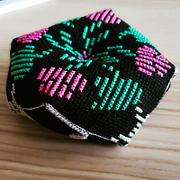 a cross stitch biscornu decorated with designs from a 90s video game